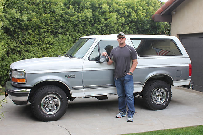 Steve Austin posing with his white-blue 1995 Ford Bronco